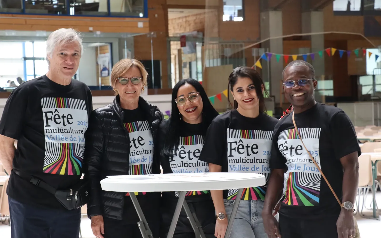 Cinq personnes portant le t-shirt de la Fête multiculturelle dans la salle